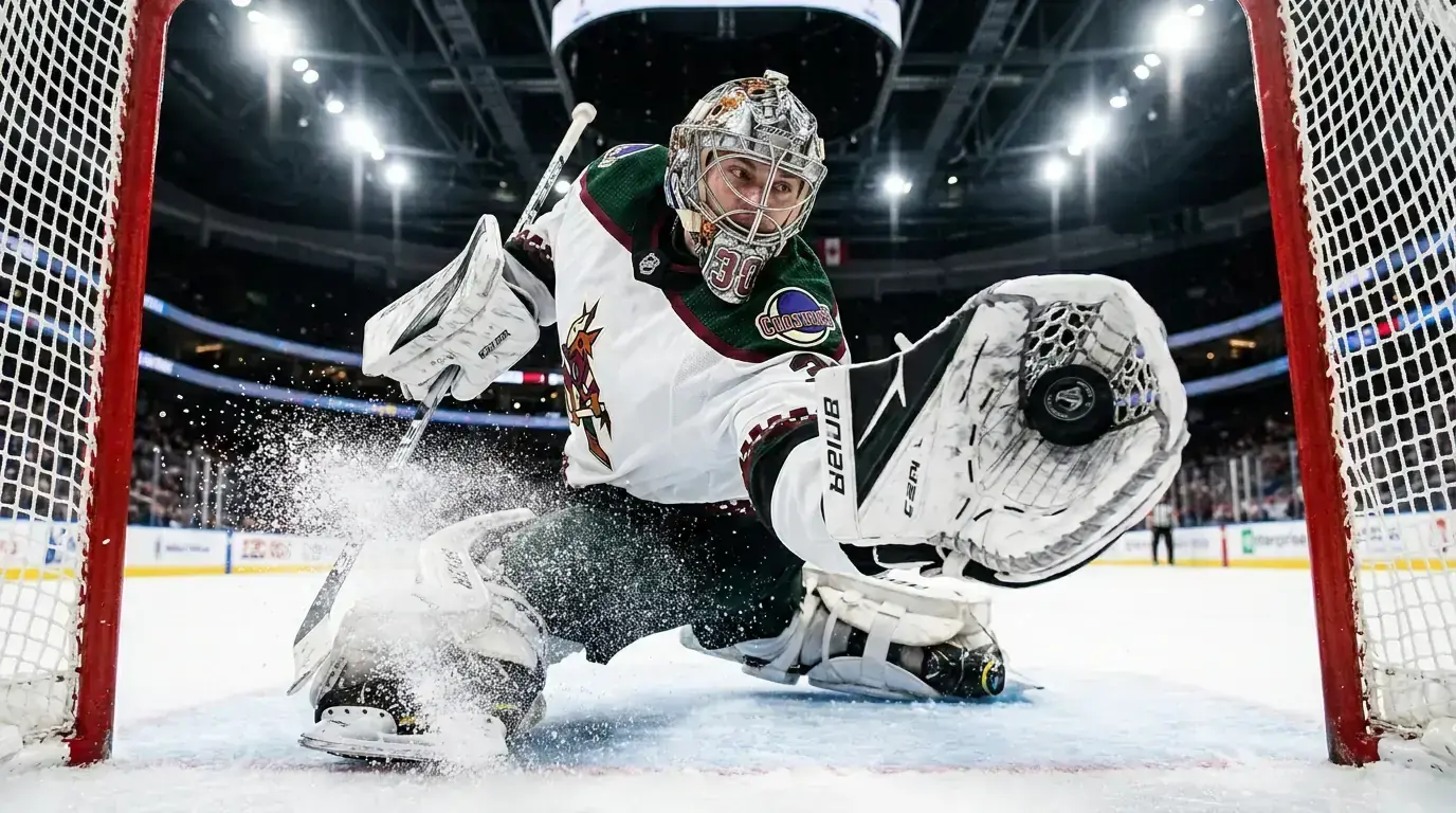 NHL goaltender in full equipment making a glove save with the puck visible against the catching mitt